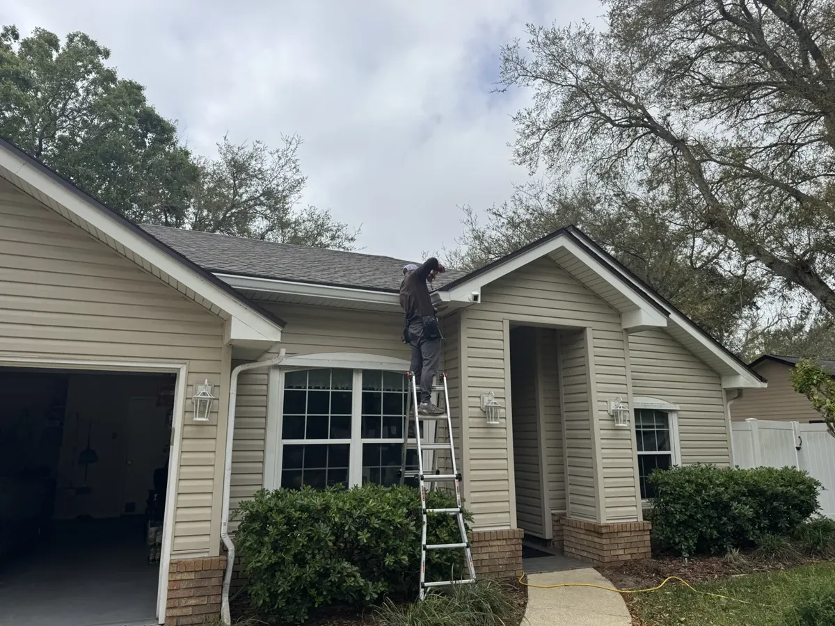 LePierre Roofing gutter installer on a ladder at the front of a home