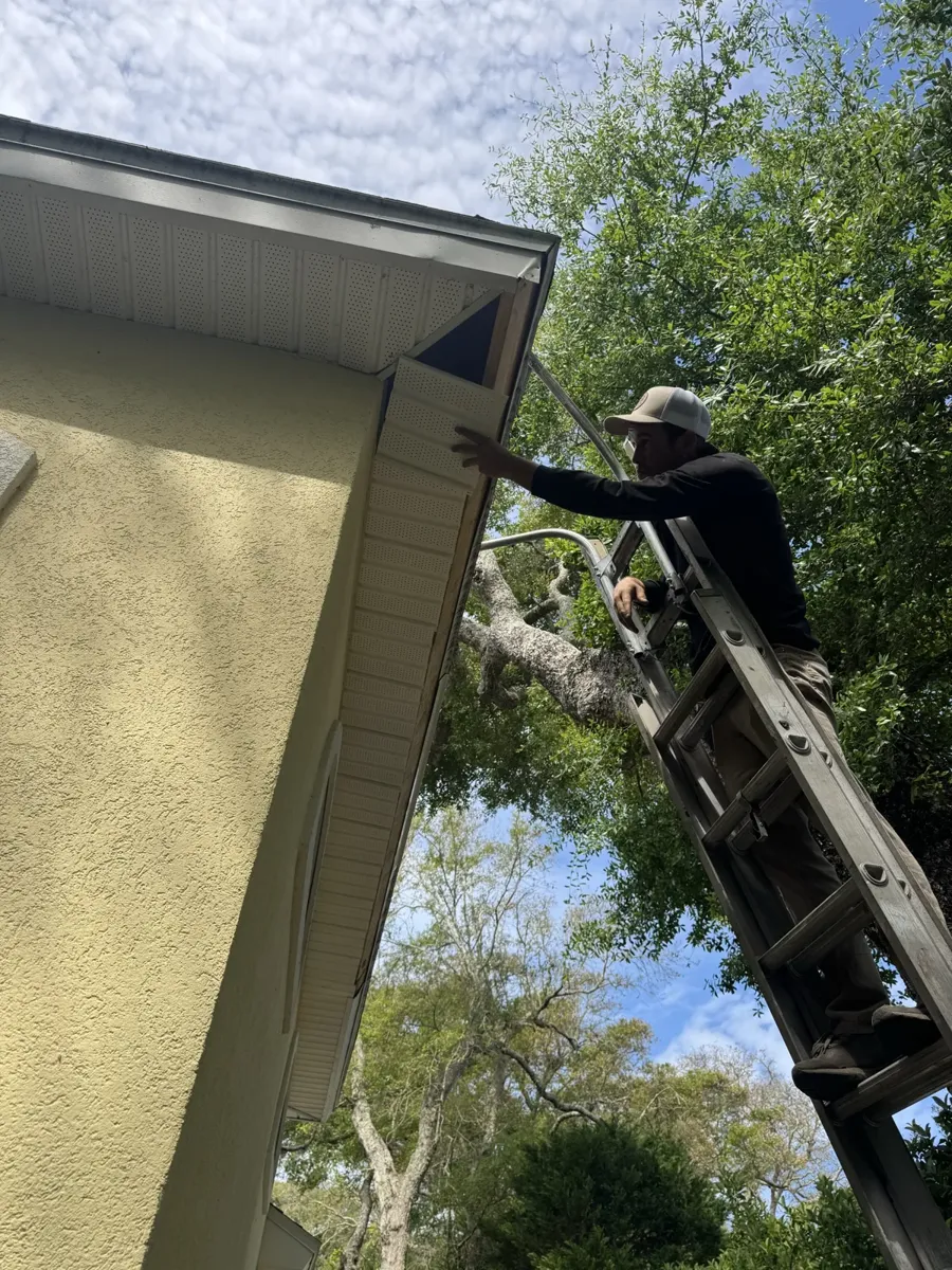LePierre Roofing gutter installer fastening a gutter from a ladder