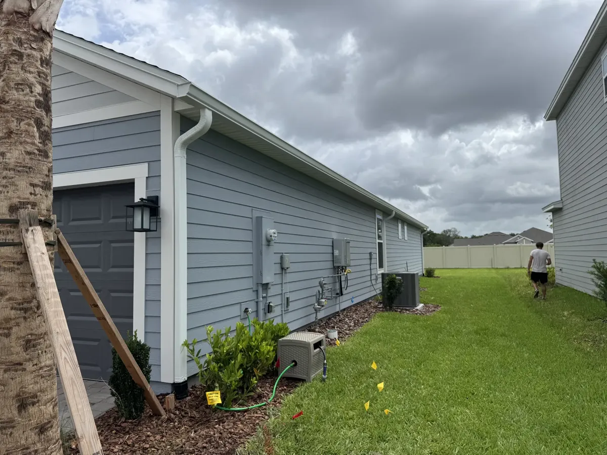 Seamless gutters and downspouts installed by LePierre Roofing on a gray siding home