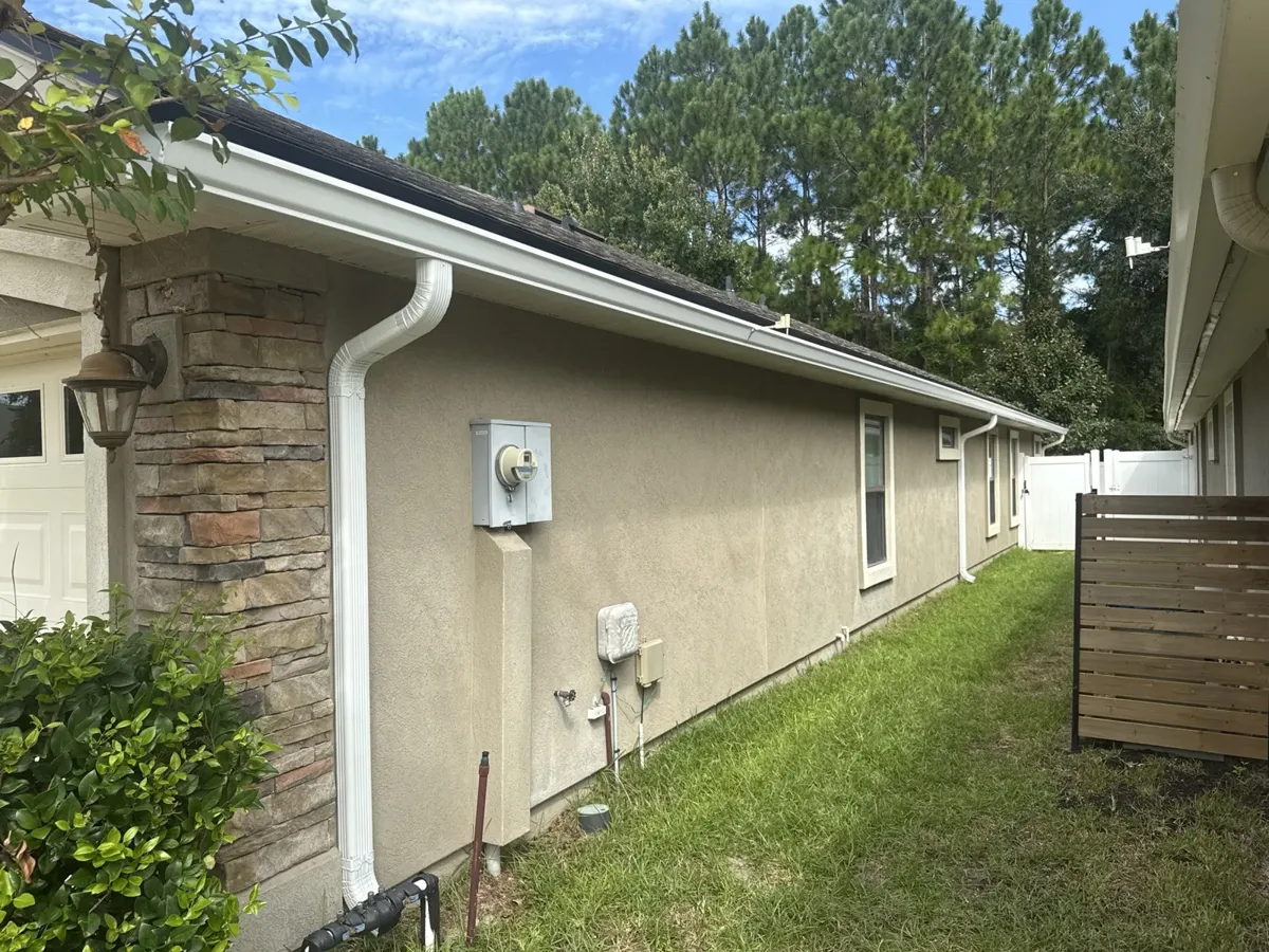 White seamless gutters and downspout installed by LePierre Roofing on a stucco home