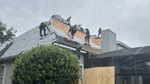 LePierre Roofing crew tearing off an old roof with plywood protecting the home